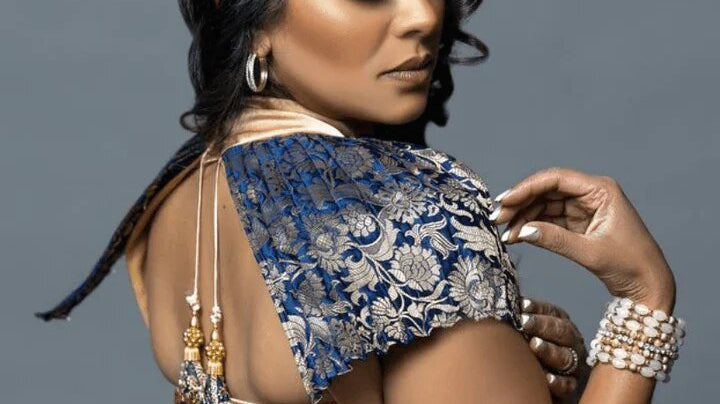 a model in a gold dress with a blue velvet shoulder detail