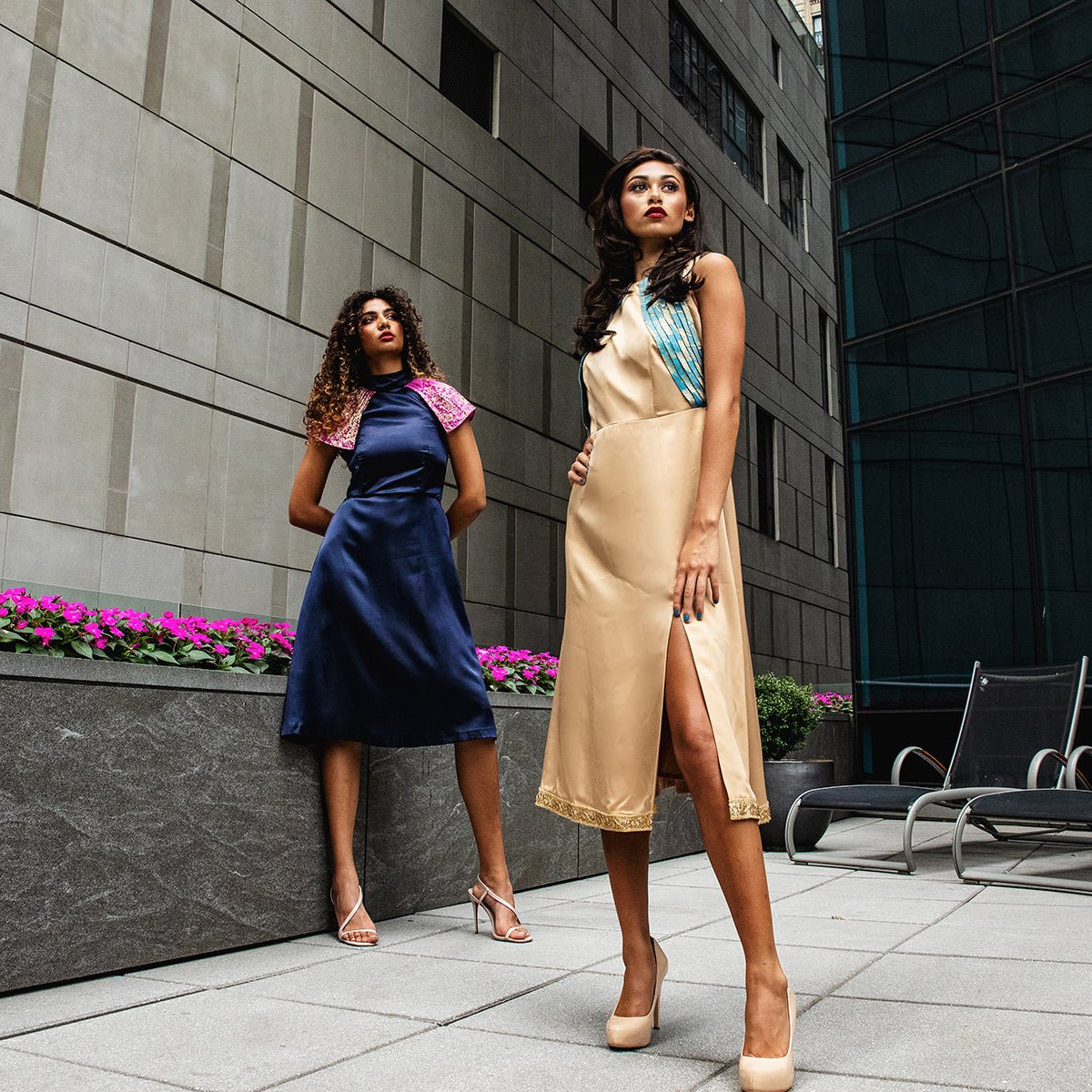 two women standing on a roof in coctail dresses