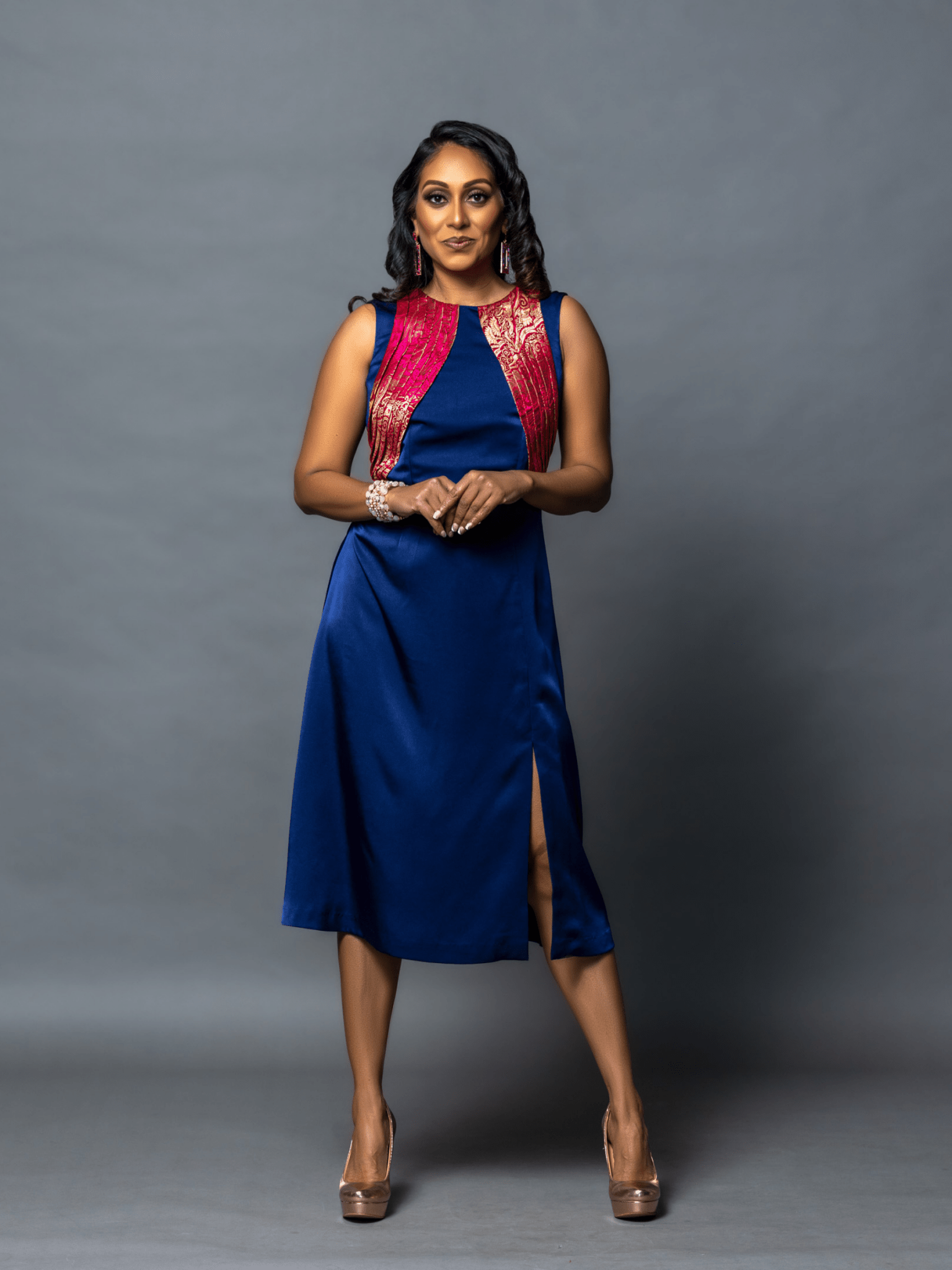 Woman wearing a blue dress with a red vest against a gray background