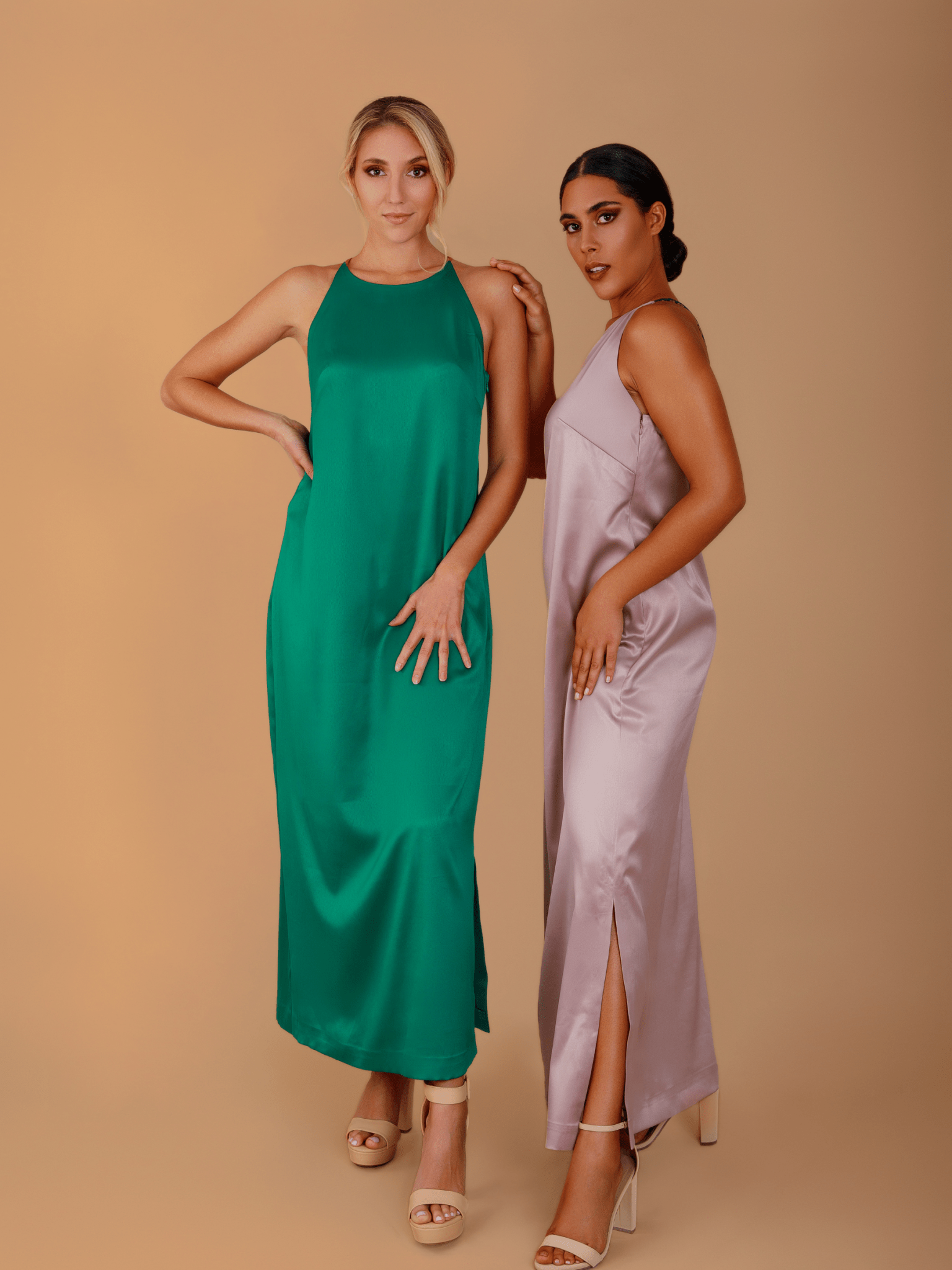 Two women wearing satin dresses against a beige background