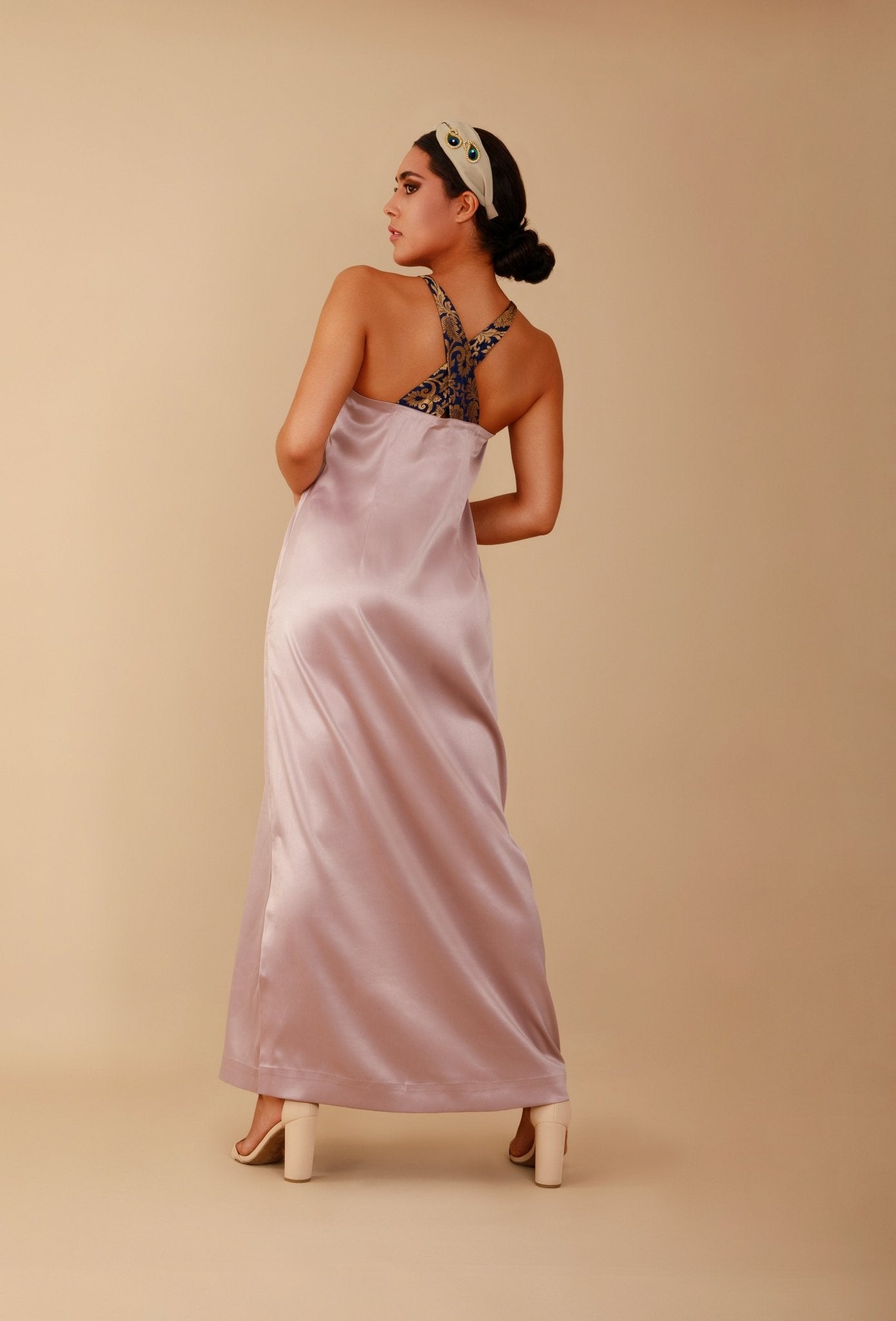 Woman wearing a long, light pink satin dress with a lace bodice on a beige background