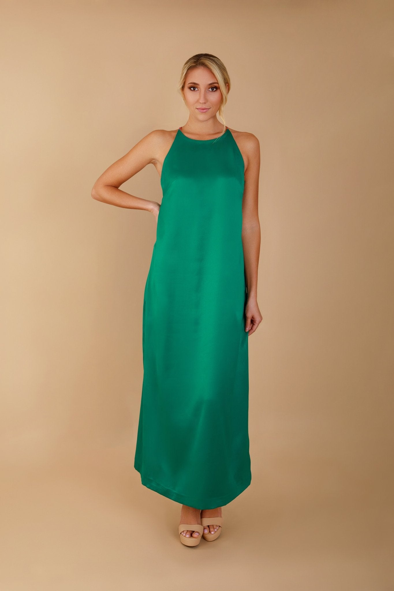 Woman wearing a green dress against a beige background