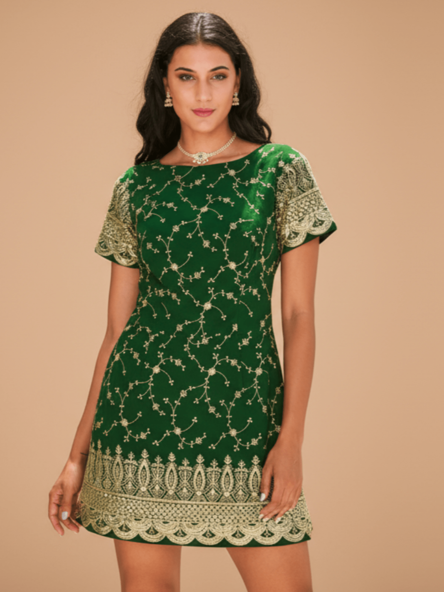 Woman wearing a green dress with gold patterns on a beige background