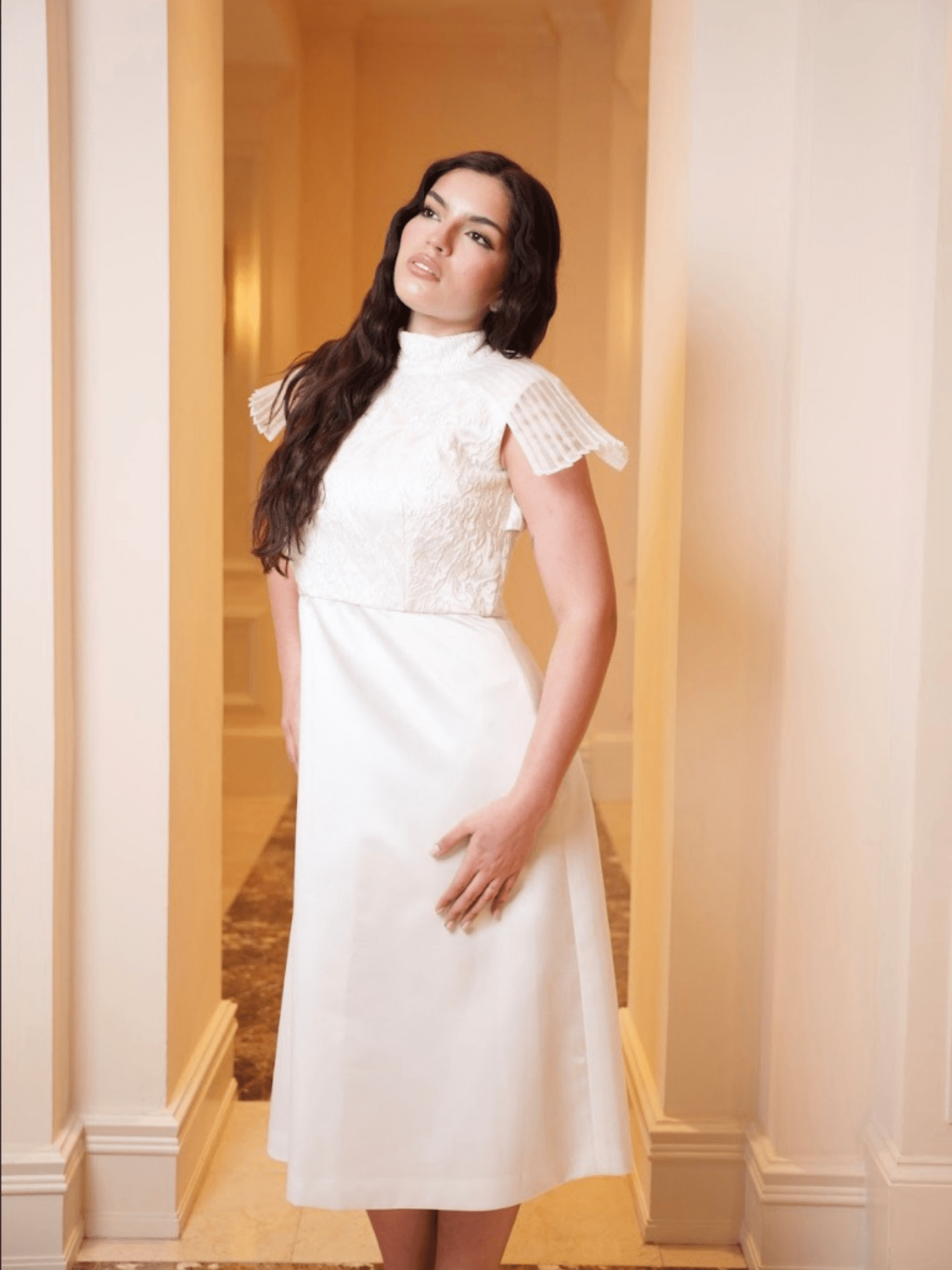 Woman wearing a white dress with lace details in an elegant interior setting