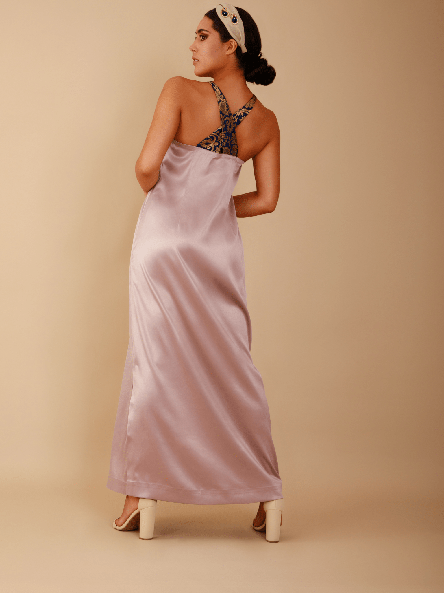 Woman wearing a long, light purple satin robe over a black lace nightgown on a beige background