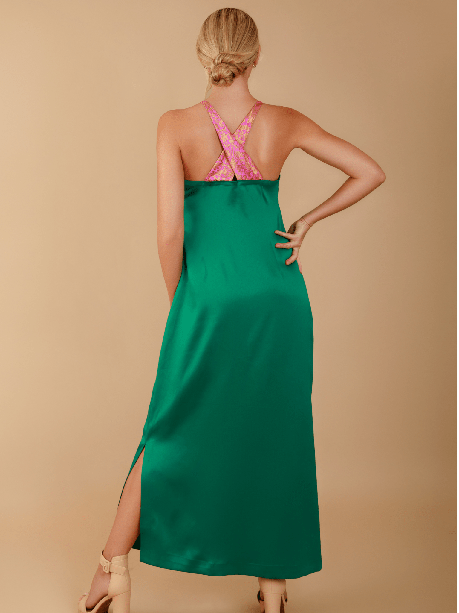 Woman wearing a green dress with a pink top on a beige background