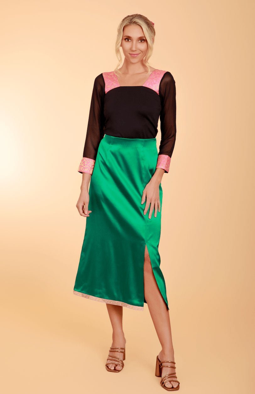 a model in a black long-sleeved top and green satin skirt
