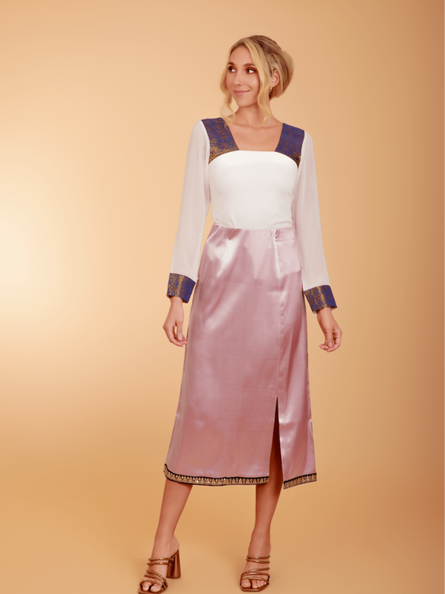 Woman wearing a white blouse with blue accents and a pink skirt on a beige background