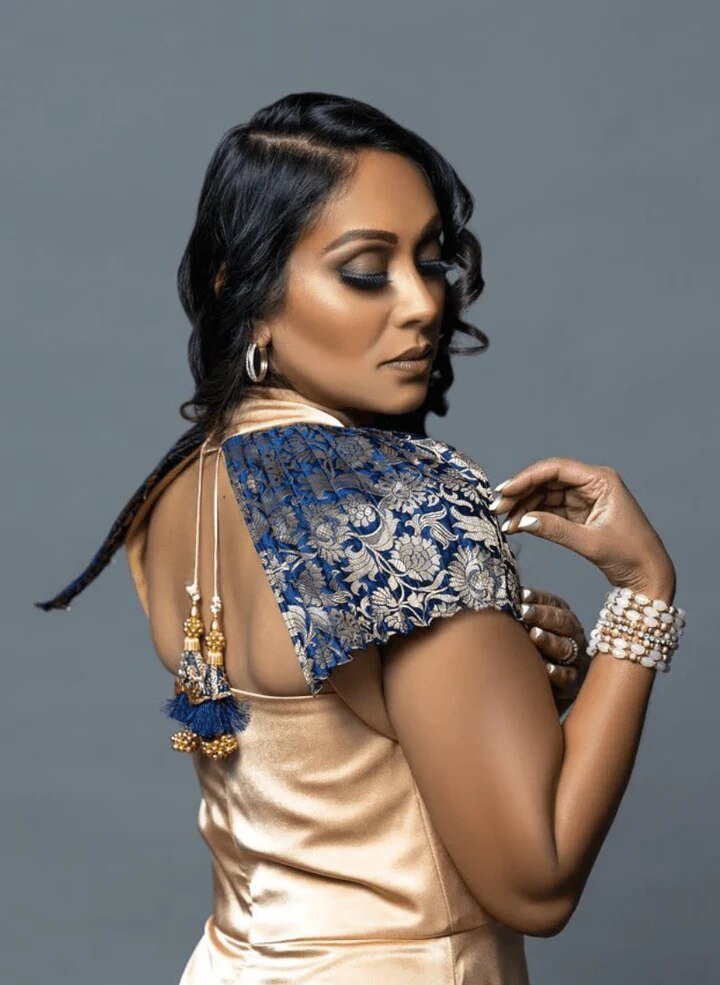 a model in a gold dress with a blue velvet shoulder detail