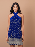Woman wearing a blue dress with intricate patterns on a beige background