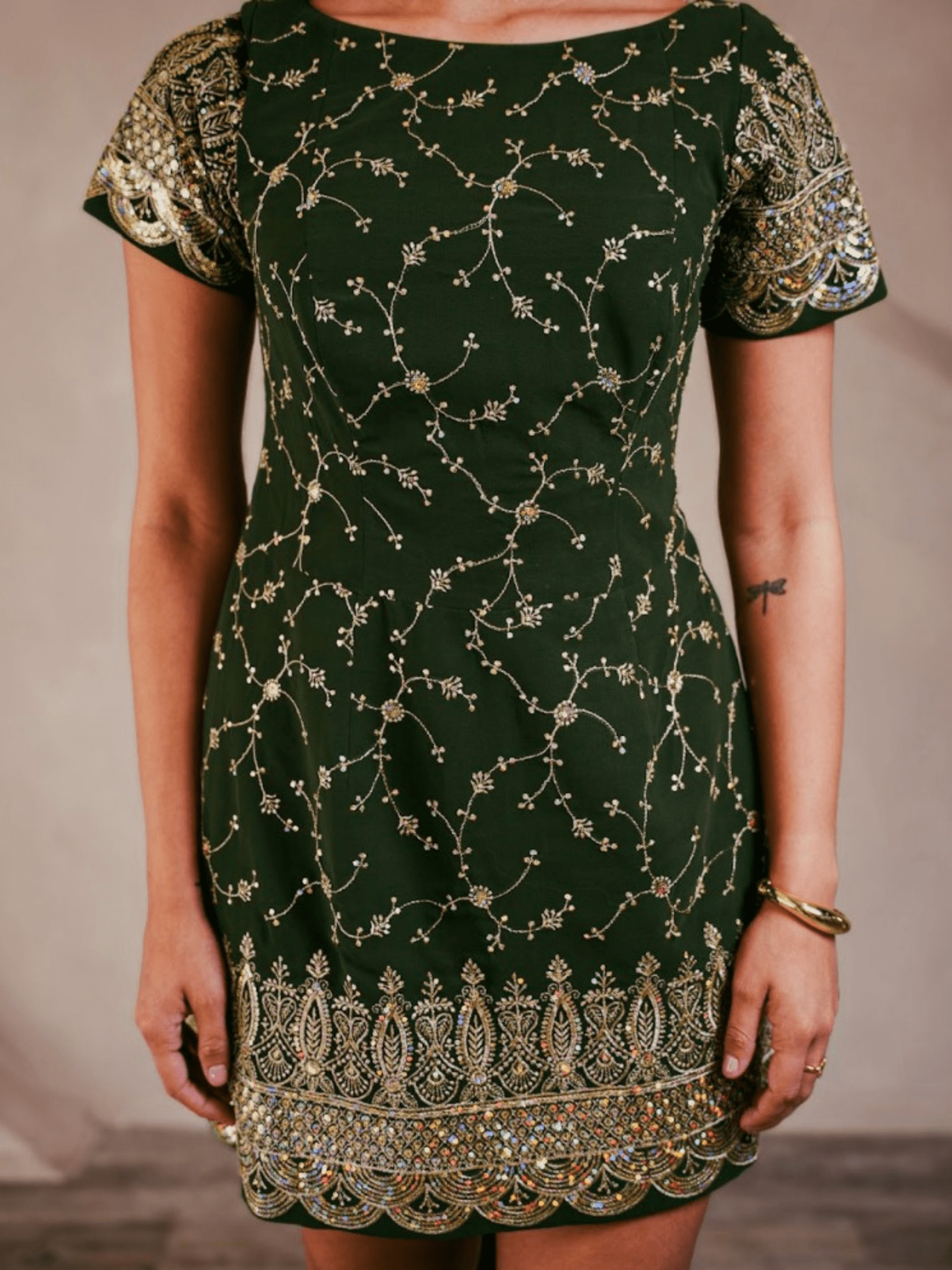 Green dress with gold embroidery on a plain background