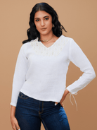 Woman wearing a white blouse with lace details on a beige background