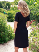 Woman in a white dress with a red belt standing in a garden setting