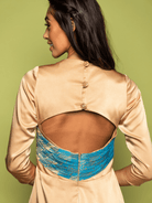 Woman wearing a beige blouse with a blue lace detail on a green background