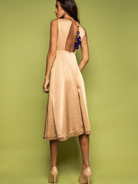 Woman wearing a beige dress with floral details on a green background