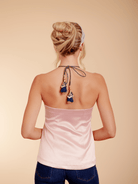 Woman wearing a strapless top with decorative tassels on a beige background