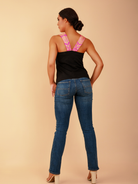 Woman wearing a black top and blue jeans on a beige background