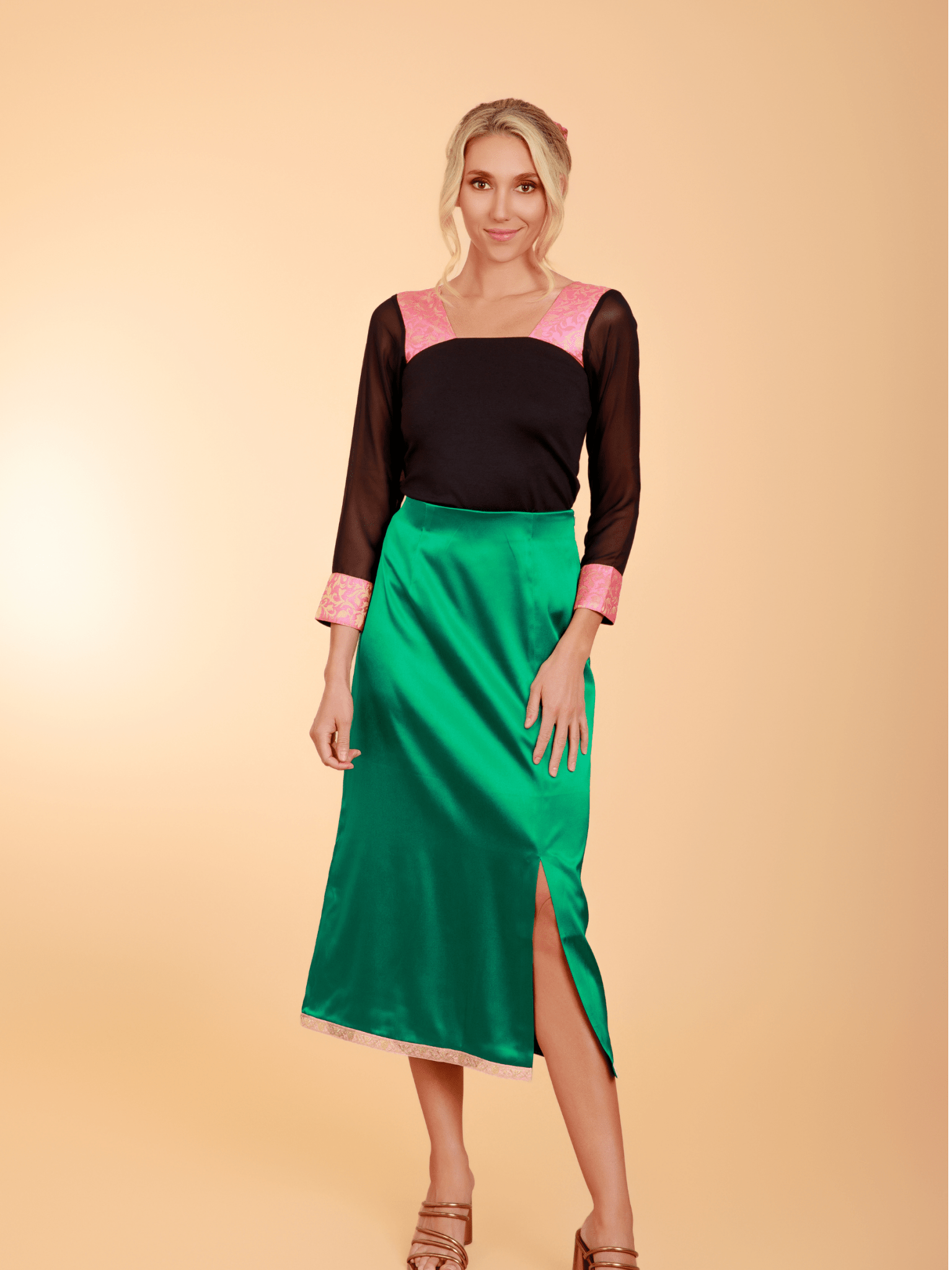 Woman wearing a black top with pink sleeves and a green skirt on a beige background