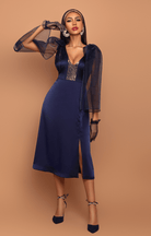 Woman wearing a blue dress with sheer sleeves against a brown background