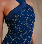Blue dress with intricate gold embroidery on a neutral background
