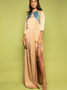 Woman wearing a long beige dress with blue accents on a green background