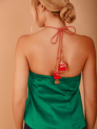 Woman wearing a green strapless top with decorative back ties on a beige background