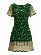 A dark green short-sleeve dress with intricate gold floral embroidery and a decorative gold lace hem, shown against a plain white background.