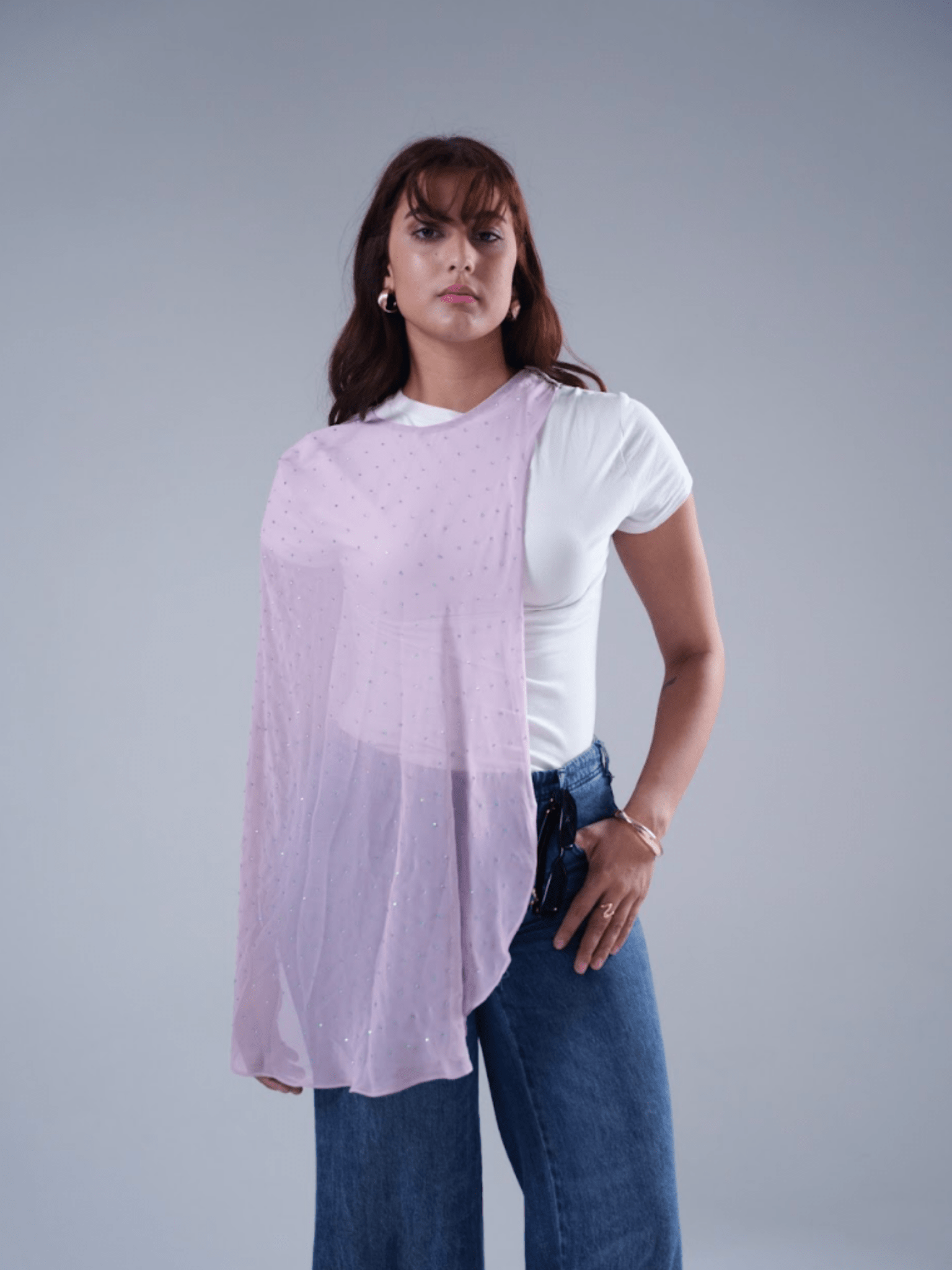 Woman wearing a light purple scarf over a white shirt with a gray background