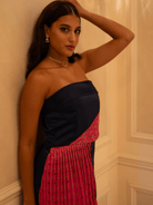 Woman wearing a strapless dress with black and red pattern against a beige wall.