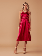 Woman wearing a red satin dress against a beige background