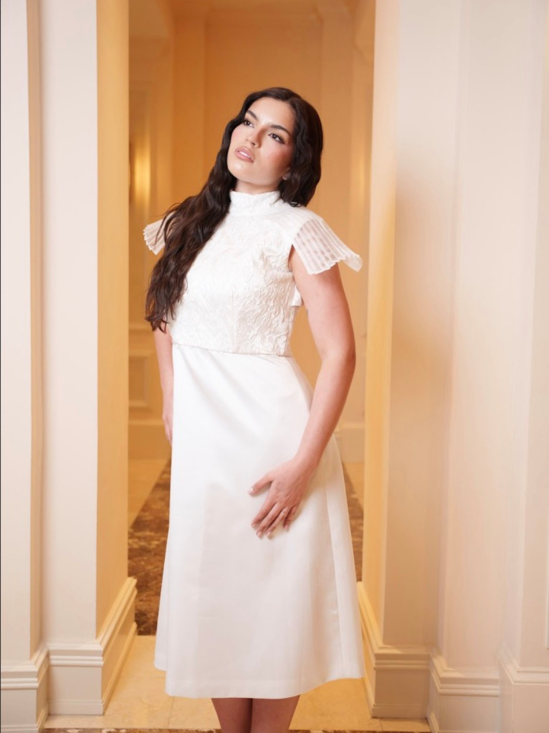 Woman wearing a white dress with lace details in an elegant interior setting
