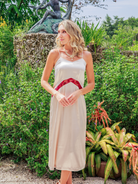 Woman in a white dress with red trim standing in a garden setting