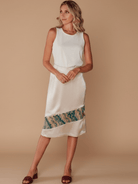 Woman wearing a white dress with a colorful hem on a beige background