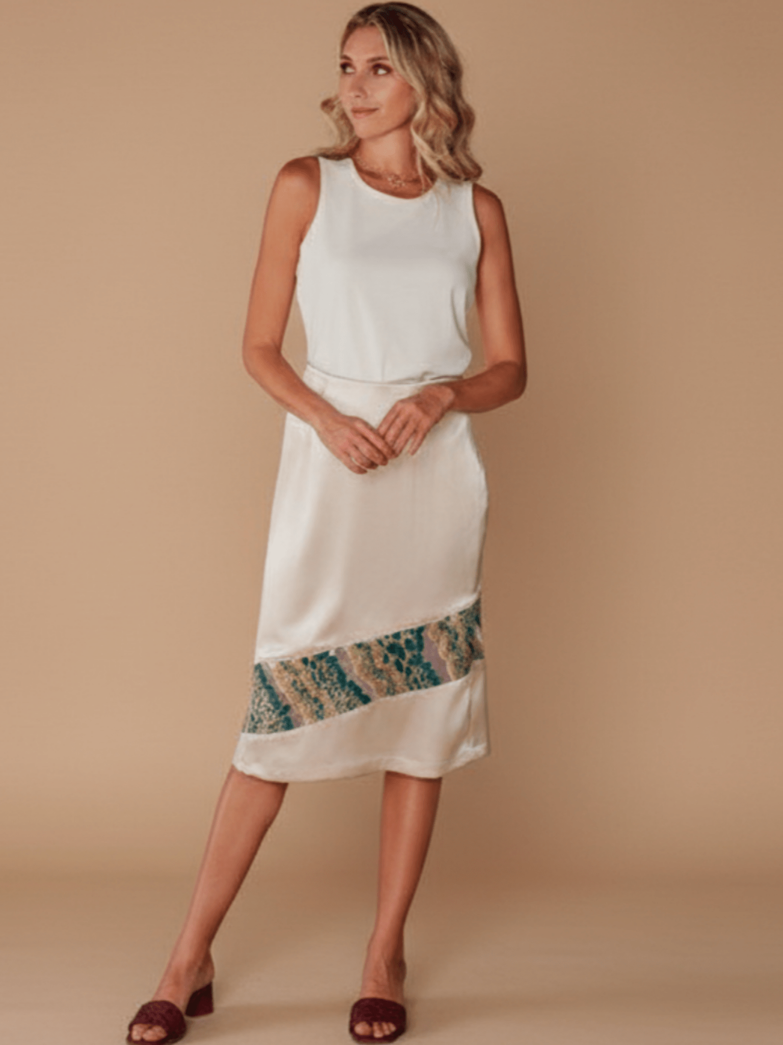 Woman wearing a white dress with a colorful hem on a beige background