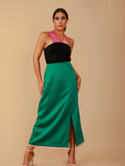 Woman wearing a black top and green skirt against a beige background