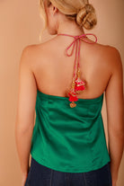a model facing away from the camera in dark denim and a green satin halter neck top