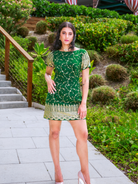 Woman in a green dress standing outdoors with greenery in the background