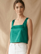 La' Agra emerald green satin sleeveless crop top with a square neckline worn by a model against a neutral backdrop