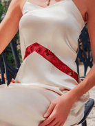 White dress with a red sequin detail on a person sitting outdoors.