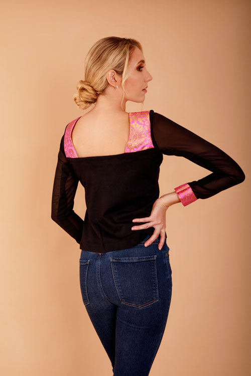 a model showing the back of a black long-sleeve top with pink details