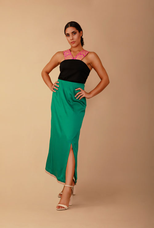a model in a black halter top and green satin maxi skirt
