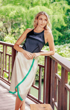 a model in a black top and cream skirt with green detail