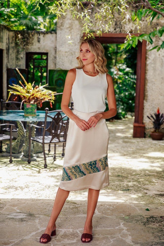 a model in a cream top and skirt with green and gold floral details