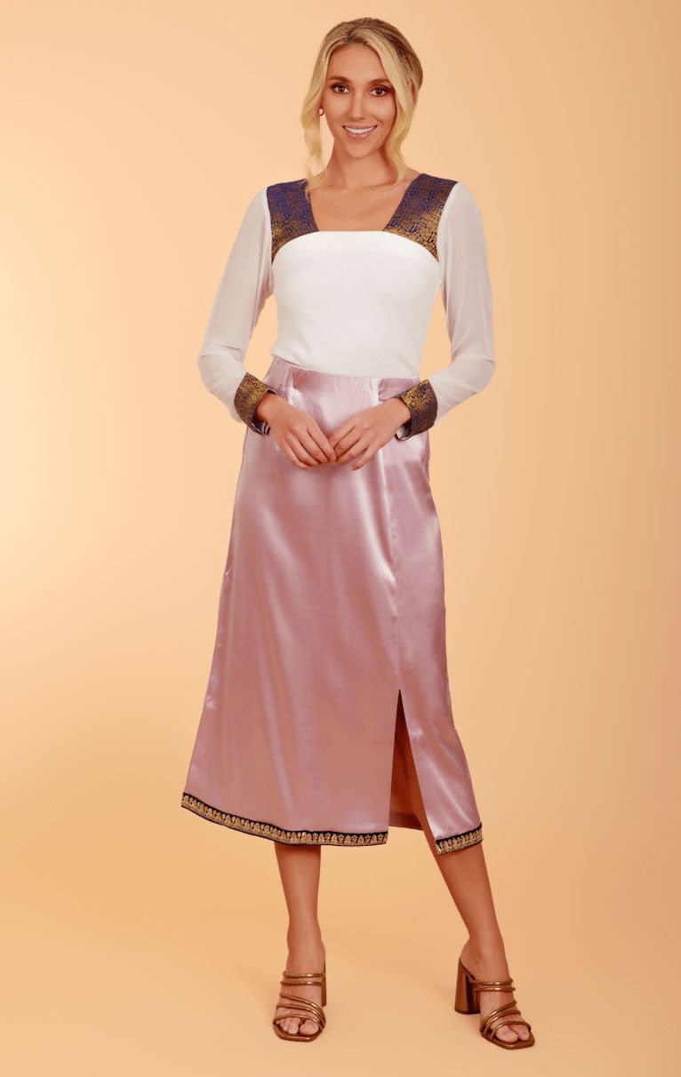 a model in a white long-sleeved top and pink satin skirt