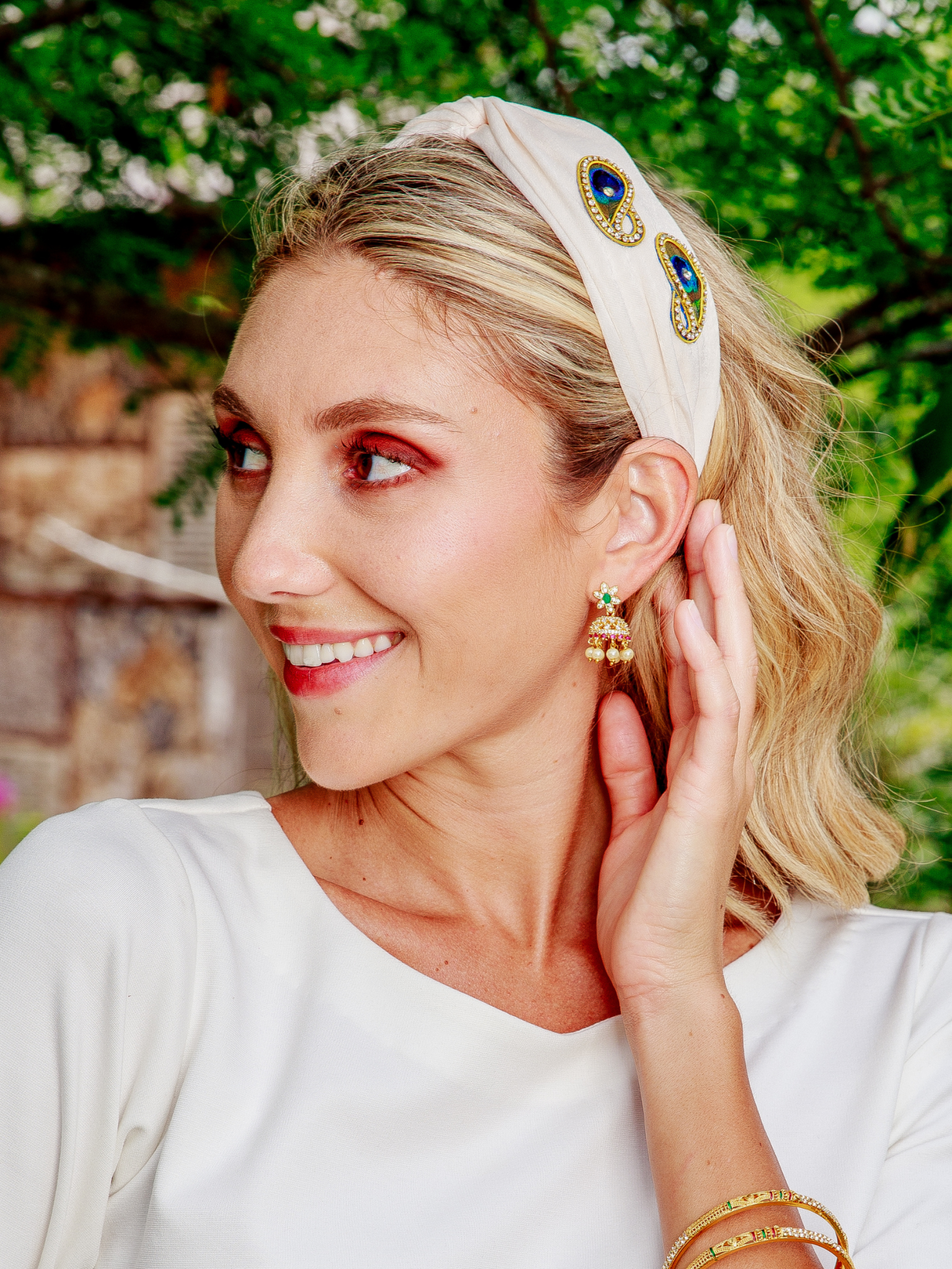 Woman wearing a headband and earrings with a blurred green background